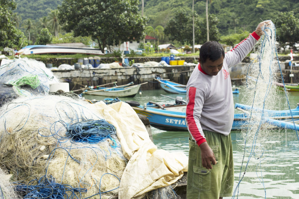 Man on boat untangles fishing gear.