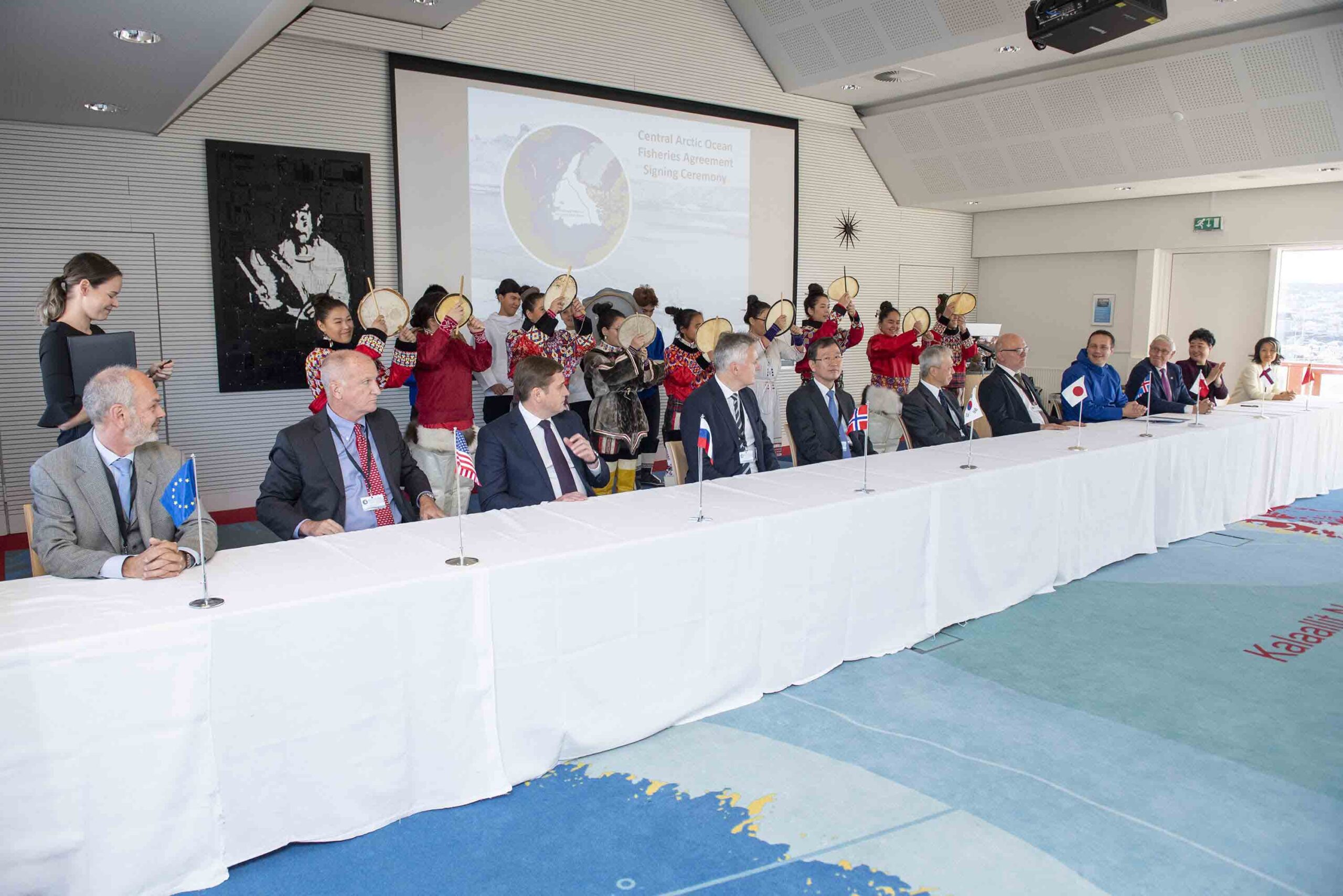 Signatory photo in Nuuk, Greenland with local drummers in traditional dress of Greenland in background.