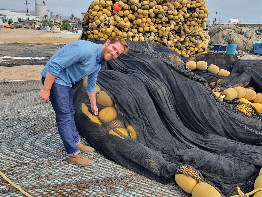 Man stands with fishing nets being recycled