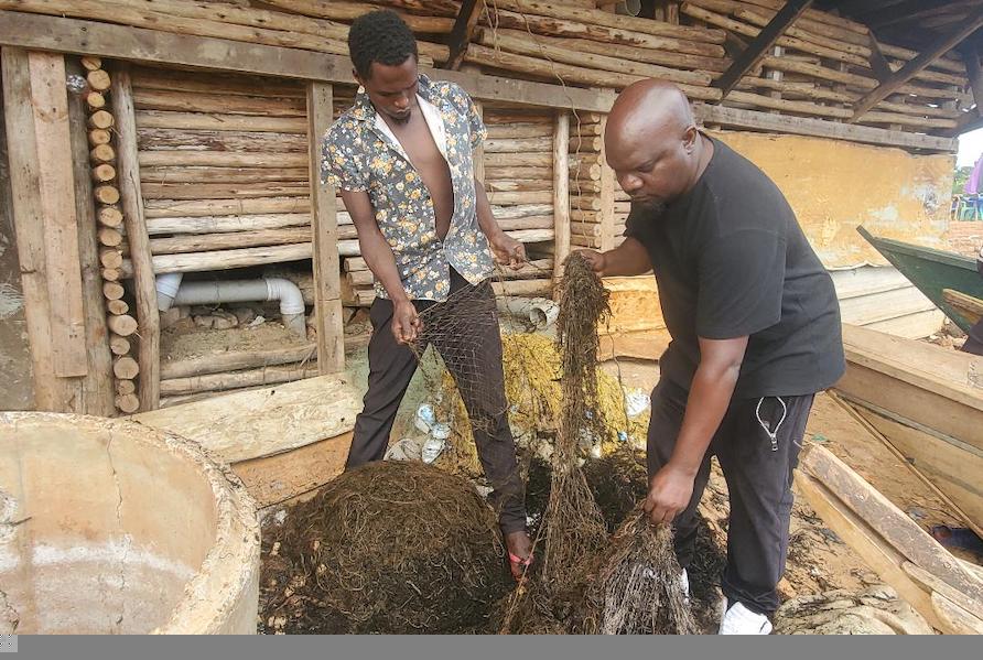 Global Ghost Gear Mutumba Faisal in dressed Black, the Director of Uganda Junior Rangers and John Mubiru a fisherman in Uganda, sorting recovered discarded fishing gear before cleanup and storage by Uganda Junior Rangers